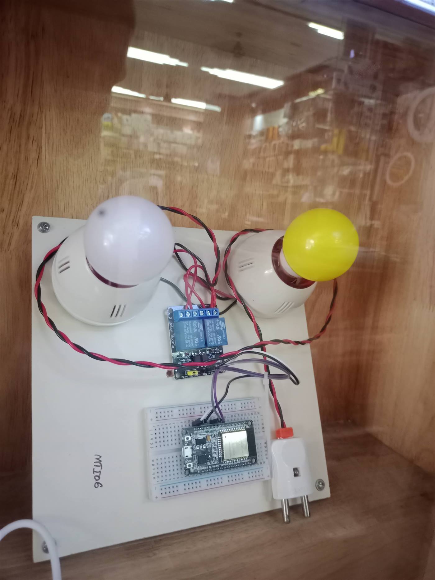 ESP32 development board wired to a 2-channel relay module controlling two bulbs
