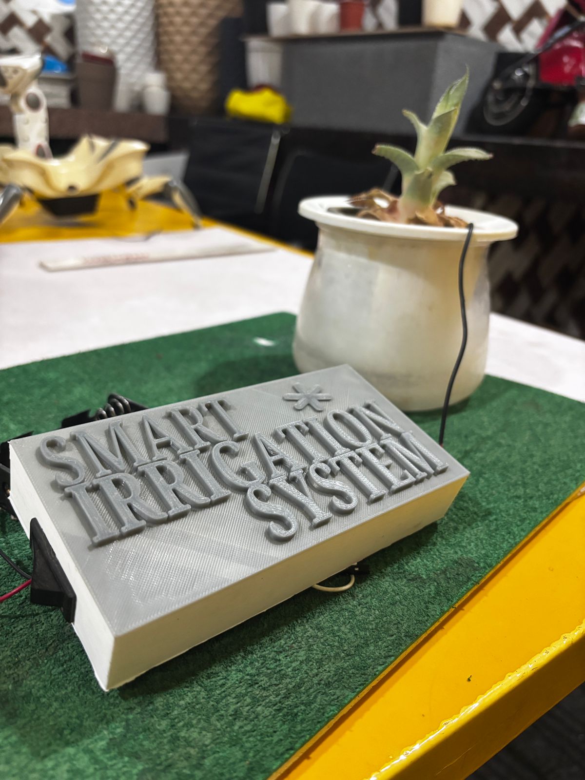 3D-printed smart irrigation system enclosure next to a potted plant with a soil moisture probe